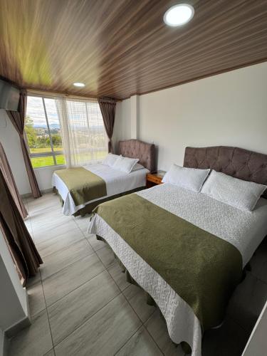 a bedroom with two beds and a large window at Tauko Tú Casa in Paipa