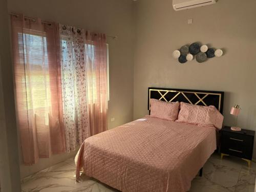 a bedroom with a bed with pink sheets and a window at Op paradise living in Kingston