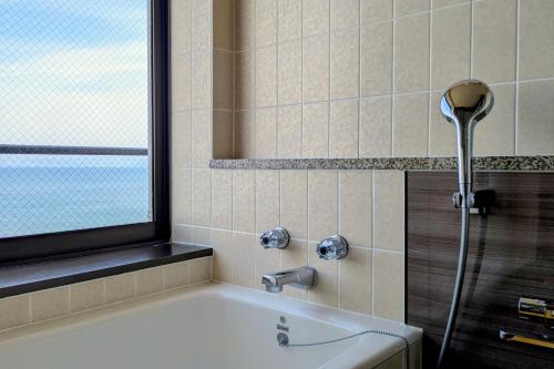 a bathroom with a bath tub with a shower at 夫婦露天風呂の宿吟松 in Ibusuki