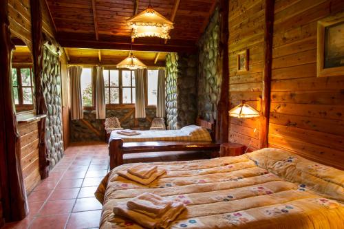 1 dormitorio con 2 camas en una cabaña de madera en Morada del Sol - Experiencia de Montaña en El Bolsón