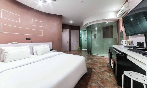 a bedroom with a large white bed and a kitchen at Paju Picasso in Paju