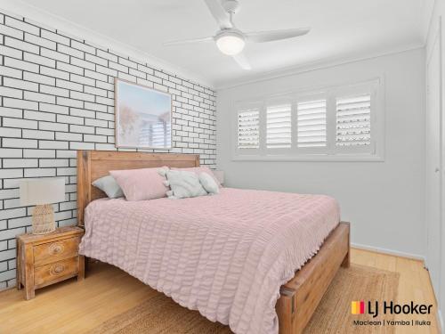 a bedroom with a bed with a pink comforter at Barefoot by the Bay in Iluka