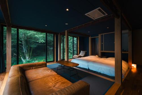 a bedroom in a house with a bed and a couch at Boscage Kariya in Yugawara