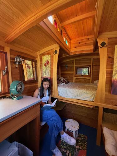 Ein Mädchen sitzt in einem Zimmer in einer Hütte in der Unterkunft Bitty Bunky in Nelson