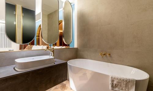 a bathroom with a tub and a sink and mirrors at Hotel Mayotte in Uiwang