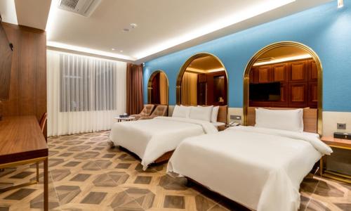 two beds in a room with a blue wall at Hotel Mayotte in Uiwang
