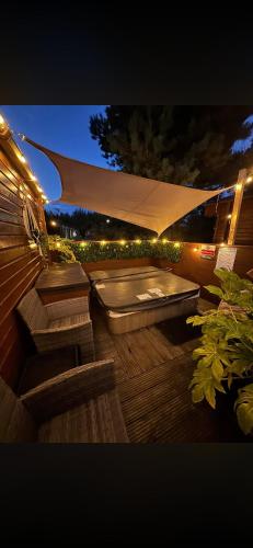 a hot tub on a deck with an umbrella at Olive Tree Lodge in West Thirston