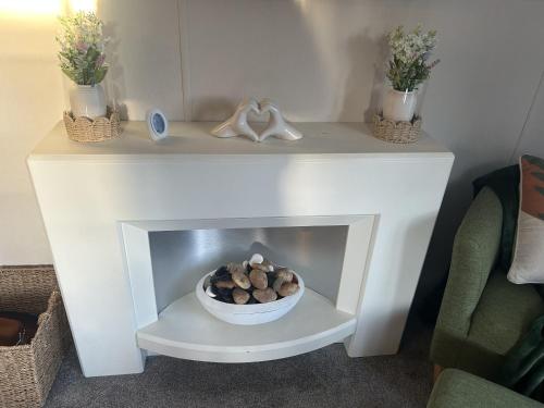 a white fireplace with a bowl of logs in it at Olive Tree Lodge in West Thirston