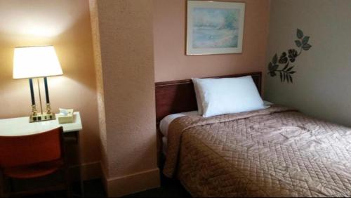 a hotel room with a bed and a lamp and a table at A Voyageur's Guest House in Ottawa