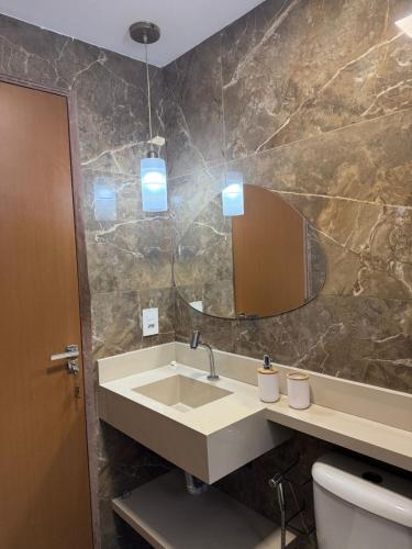 a bathroom with a sink and a mirror and a toilet at Flat ipojuca in Caruaru