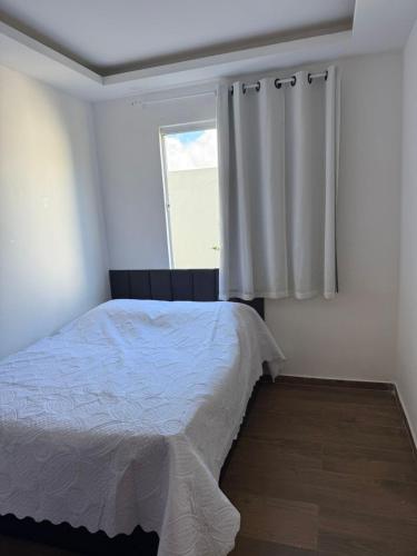 a bedroom with a white bed and a window at Flat ipojuca in Caruaru