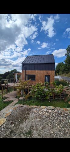 a small house with a black roof on a field at Domek DOMiarki in Klecza