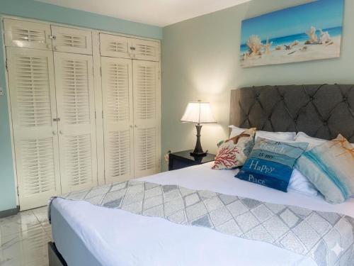 a bedroom with a bed with white furniture and a lamp at Sea Castles La Vue in Montego Bay