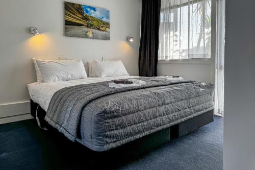 a bedroom with a bed with a blanket and a window at Recreation Hotel in Greymouth