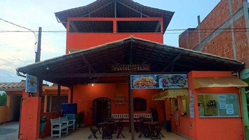 an orange building with a restaurant with tables and chairs at Pousada Portal da Ilha in Itaoca