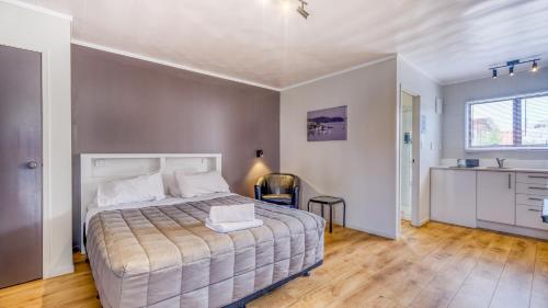 a bedroom with a large bed and a kitchen at Wayfarer Motel in Kaitaia