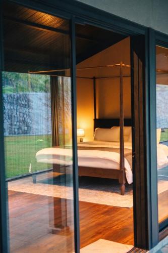 a bedroom with a canopy bed and a glass window at Spring River Cisarua in Paragajen