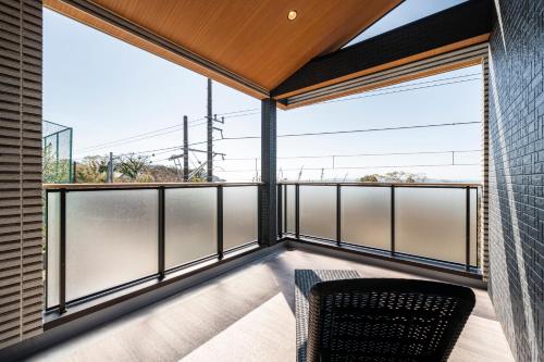 a room with a balcony with a chair and large windows at YUTORELA 富津 indoor GOLF シミュレーションゴルフ付き l BBQ l ファミリー歓迎 in Futtsu