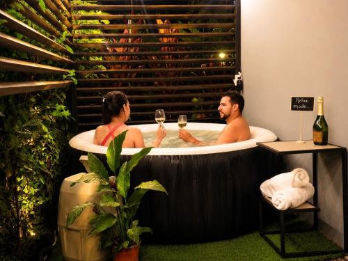 a man and woman in a bath tub with wine glasses at The Slothie's House in Fortuna