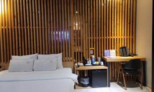 a bedroom with a bed and a desk and a chair at Jinhae Pasta Hotel in Changwon