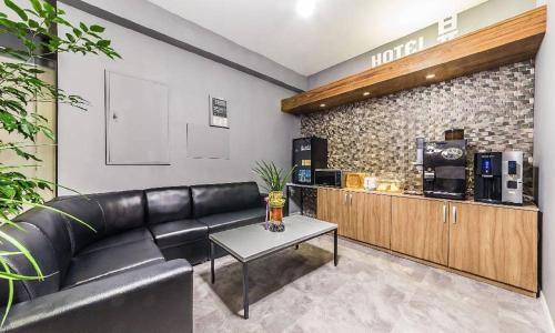 a living room with a black leather couch and a table at Chuncheon Hotel View in Chuncheon