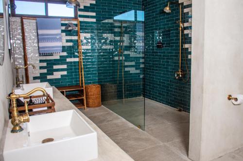 a bathroom with a sink and a glass shower at La Familia Casa and Suites in Holbox Island