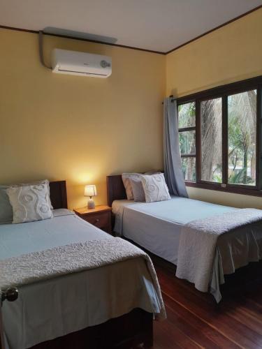 two beds in a room with a window at Riverside Oasis Cabin with A C in Guápiles