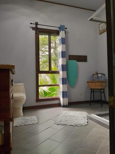 a bathroom with a toilet and a window at Riverside Oasis Cabin with A C in Guápiles