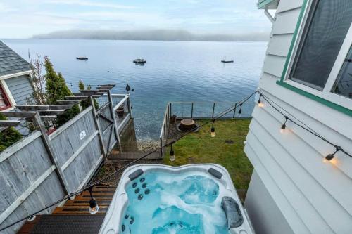 a bath tub on the side of a house next to the water at Oyster Oasis in Tahuya