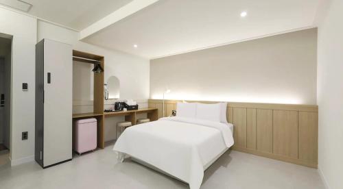 a bedroom with a white bed and a kitchen at 프라잇베리 호텔 in Chinhae