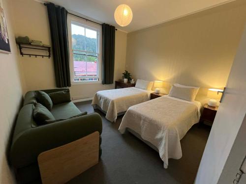 a hotel room with two beds and a couch at Nourish Reefton & Wilsons Hotel in Reefton