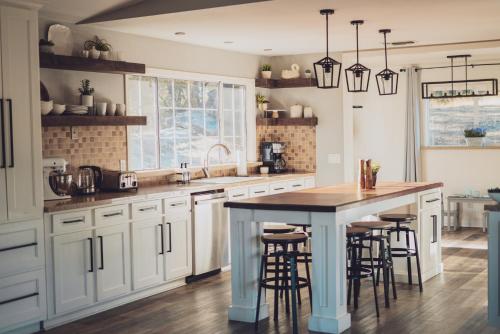 a kitchen with white cabinets and a island with bar stools at Sunset Site Boulder Bliss HotTub by Casa Oso in Ahwahnee