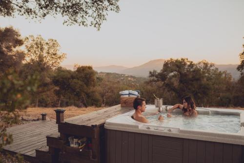 two people in a hot tub on a deck at Sunset Site Boulder Bliss HotTub by Casa Oso in Ahwahnee