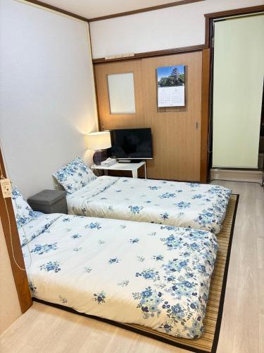 a hotel room with two beds and a television at 大阪三姐妹天下茶屋館 Three Sisters Lodge -Tengachaya in Osaka