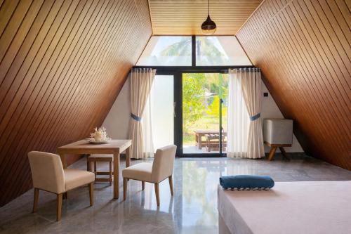 a room with a table and chairs and a window at Cottage Paramount in Udawalawe