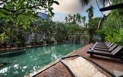 a swimming pool with a bench next to a building at Home Indochine d'Angkor Hotel in Siem Reap