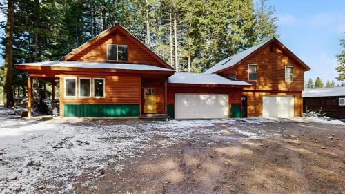 a wooden house with a garage in the snow at Rustic-Modern Cabin with Hot Tub Access in McCall