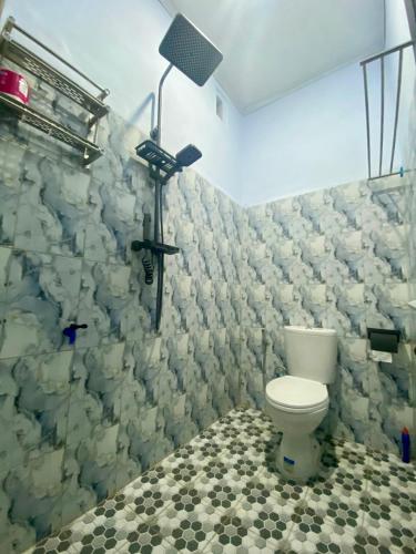a bathroom with a toilet and a light on the wall at Sulis homestay in Kuta Lombok