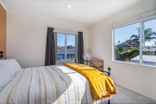 a bedroom with a bed with a yellow blanket on it at Williamson Getaway - Top Whangamata Location in Whangamata
