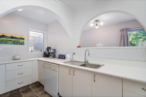a white kitchen with a sink and a window at Williamson Getaway - Top Whangamata Location in Whangamata