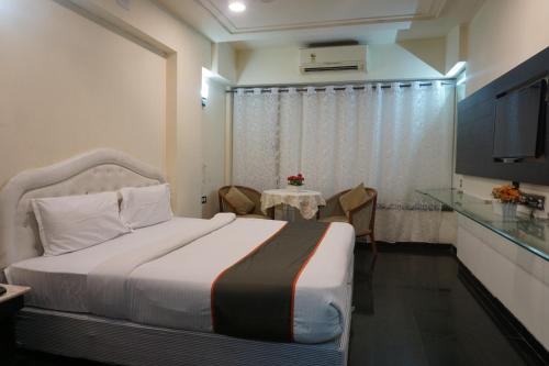 a bedroom with a bed and a table and a television at S R Rooms in Pune
