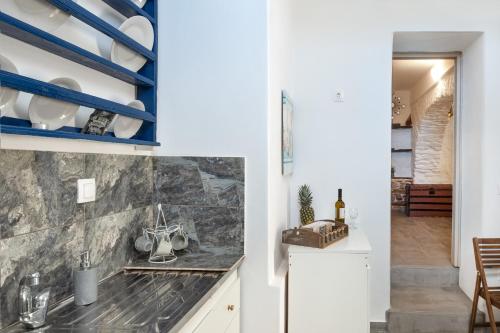 a kitchen with white cabinets and blue shelves at Olga's House kythnos D in Kithnos