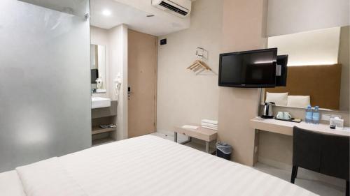 a hotel room with a bed and a tv on the wall at OS Hotel Airport Batam in Batam Center