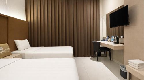 a hotel room with two beds and a desk at OS Hotel Airport Batam in Batam Center