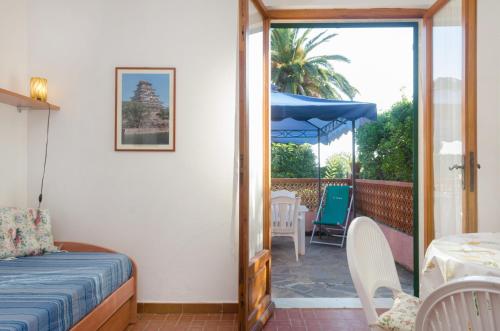 a bedroom with a bed and a patio with a table and chairs at Villa Maria Carla in Capoliveri