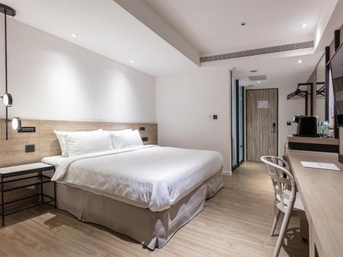 a bedroom with a large white bed and a desk at KEEBE Hotel in Keelung