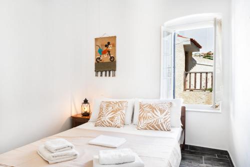 a white bedroom with a bed and a window at Olga's House Kythnos in Kithnos