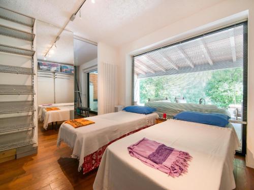 two beds in a room with a large window at Elegant villa with pool in Senigallia