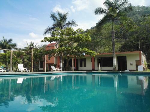 a swimming pool in front of a house with palm trees at Paraiso Inn in Satipo