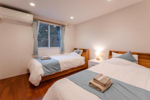 a bedroom with two beds and a window at 波の音テラス富津ー海眺望グッドデザイン受賞別荘を最大7名1棟貸切 in Futtsu